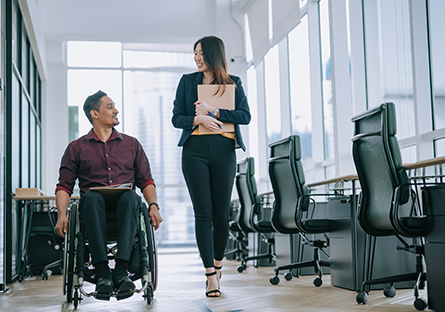 health care worker walking alongside patient in wheelchair