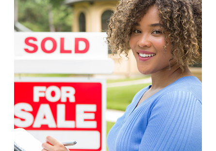 realtor in front of for sale sign with sold placard