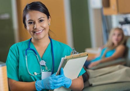 nurse holding clipboard with blurred background of patient in hospital bed