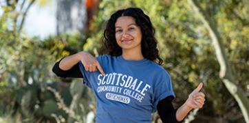 student pointing to a blue scottsdale community college tshirt