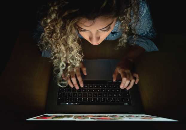 student with laptop in dark room